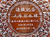 「退職記念 ○○様 長年の勤務お疲れさまでした」を底面に彫刻した、定年退職の贈り物用のガラス製灰皿