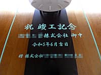 「祝竣工記念、贈り先の会社名、竣工日の日付、贈り主の会社名」を前面ガラスに彫刻した、新工場竣工祝い用の壁掛け時計